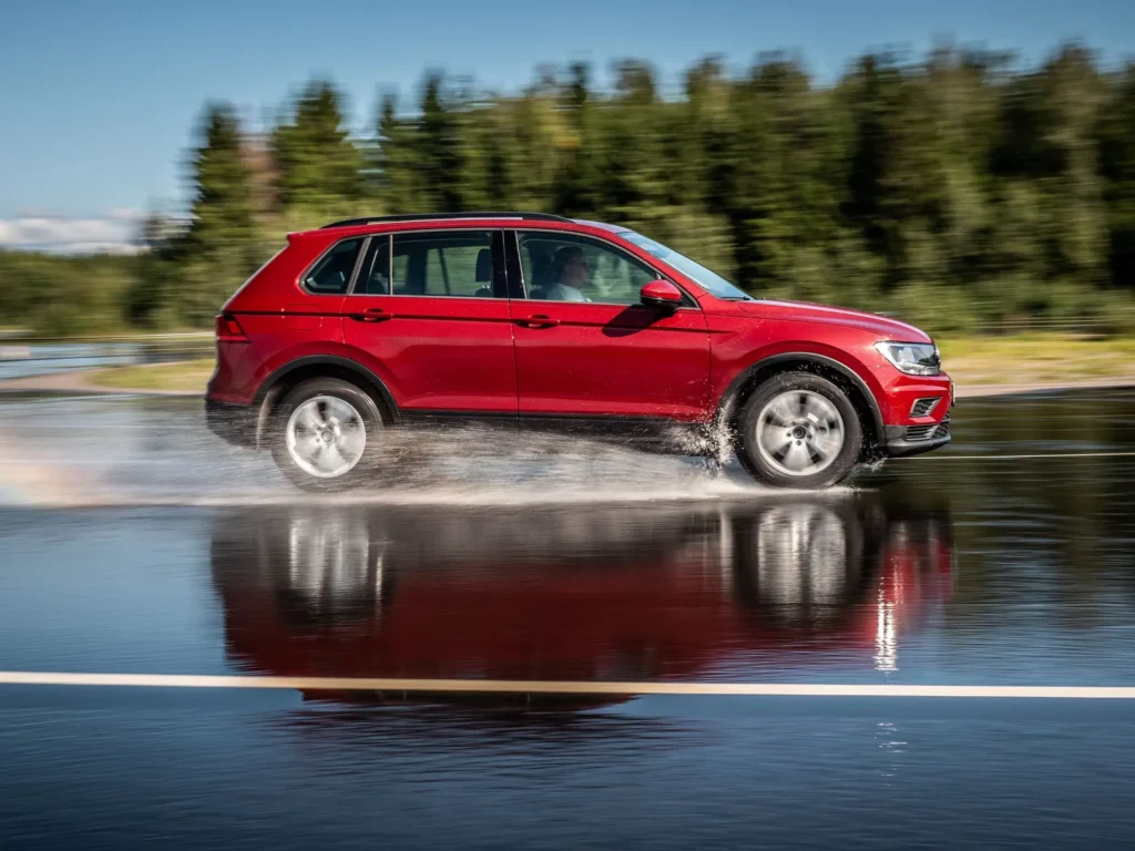 Červené auto jede po kluzké mokré vozovce 