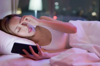 Unavená žena s mobilem v posteli