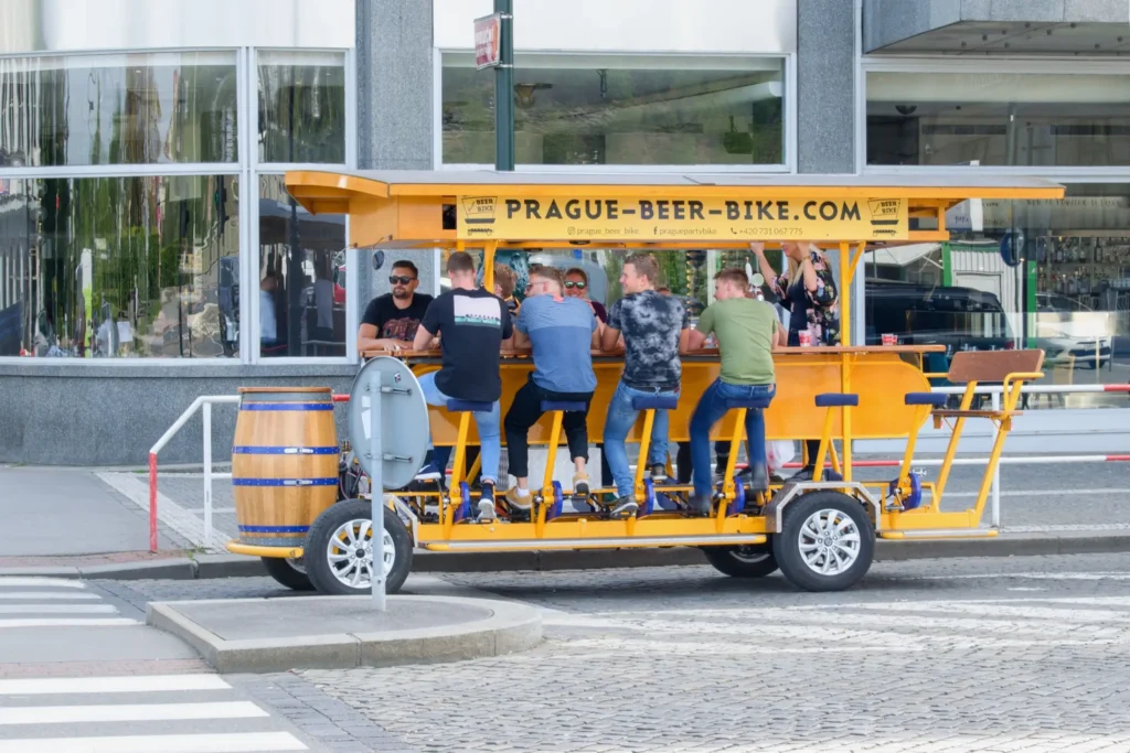 Tzv. Beerbike stojící v pražské ulici. Sedí na něm turisté.