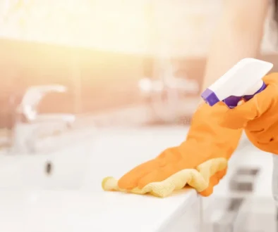 Ruce v rukavicích, houbičkou a rozprašovačem umývají umyvadlo