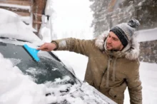 muž škrábe zamrzlé okno u auta