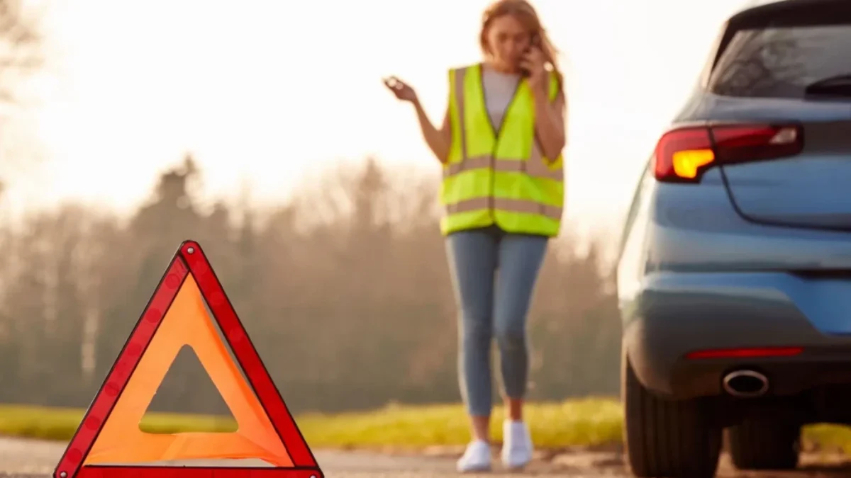 Žena v reflexní vestě umisťuje výstražný trojúhelník