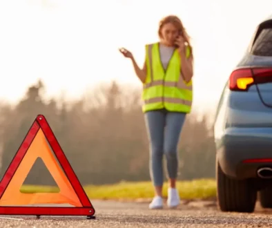Žena v reflexní vestě umisťuje výstražný trojúhelník