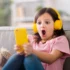 malá dívka se sluchátky a mobilem, šokovaná tím, co vidí na displeji