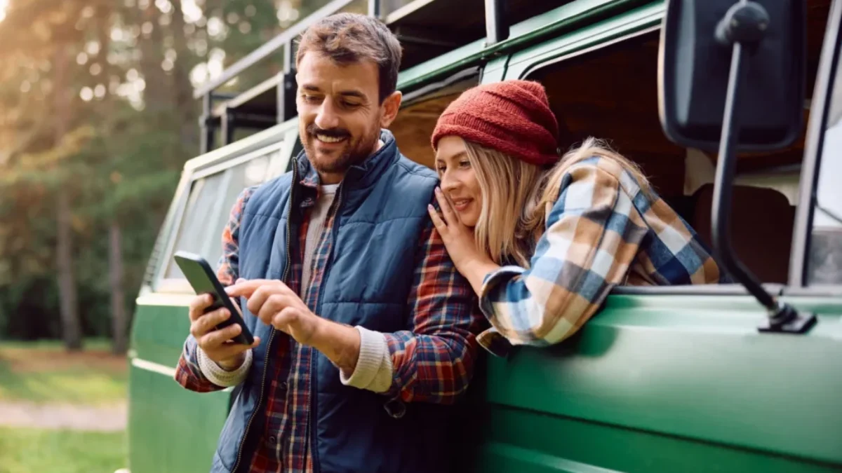pár na dovolené ve své dodávce něco hledá na telefonu