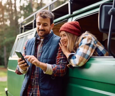 pár na dovolené ve své dodávce něco hledá na telefonu