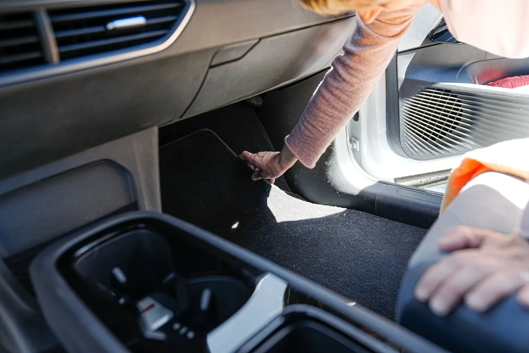 žena zvedá koberečky v autě