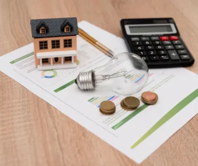 žárovka, peníze a kalkulačka na papíře