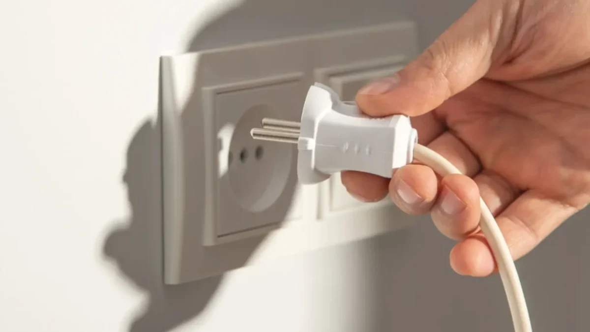 Ruka vytahující kabel z elektrické zásuvky