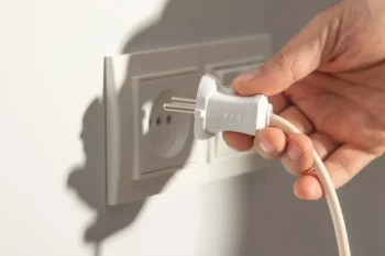 Ruka vytahující kabel z elektrické zásuvky