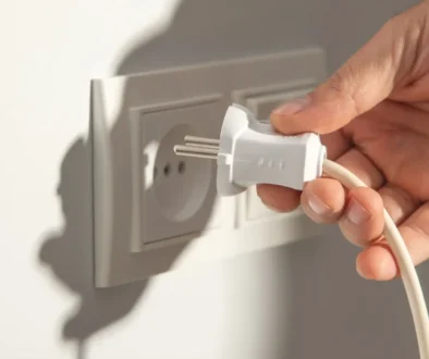 Ruka vytahující kabel z elektrické zásuvky