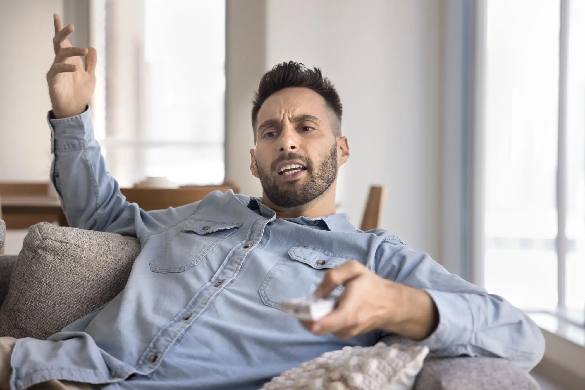 Muž nevěřícně sleduje reklamu v televizi 