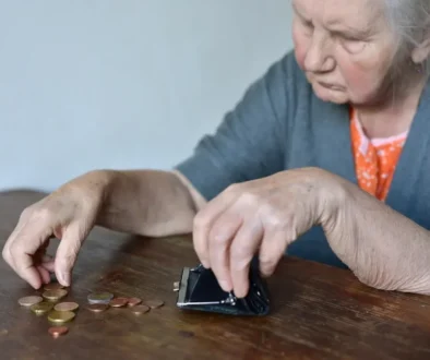 seniorka sedí u stolu a počítá drobné mince