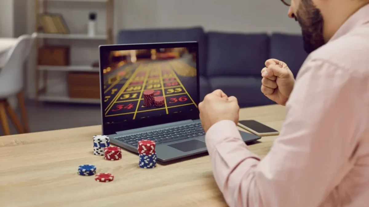 Muž sedí před notebookem a sleduje výsledky hry v casinu