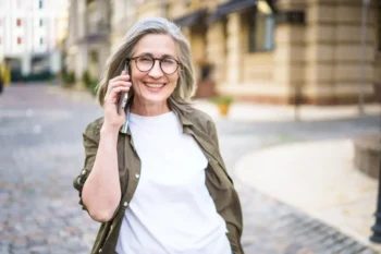 Staří žena volá mobilem a usmívá se