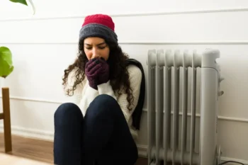 vypnuté topení, mladá žena ve svetru se třese zimou