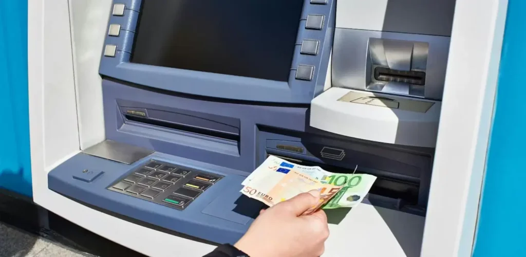 Muž vybírající z bankomatu eurové bankovky