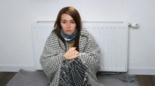 žena sedí u topení a třese se zimou
