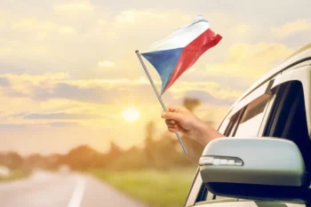 Člověk mává českou vlajkou z auta