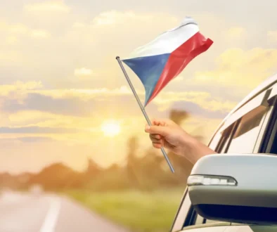 Člověk mává českou vlajkou z auta