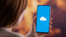 Person holding a smartphone displaying a white cloud icon on a blue screen