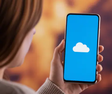 Person holding a smartphone displaying a white cloud icon on a blue screen