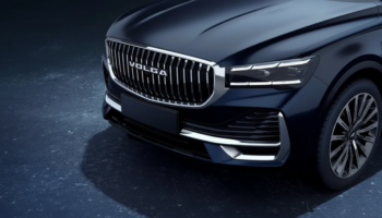 Close-up of a dark blue car front with a chrome, VOLGA grille, sharp LED headlights, and a black bumper edge.