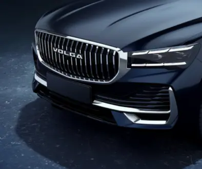 Close-up of a dark blue car front with a chrome, VOLGA grille, sharp LED headlights, and a black bumper edge.