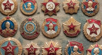 A collection of Soviet-era medal pins featuring red stars, gold wreaths, and hammer-and-sickle symbols on textured fabric.