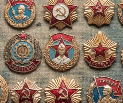 A collection of Soviet-era medal pins featuring red stars, gold wreaths, and hammer-and-sickle symbols on textured fabric.