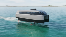 White futuristic boat elevated above turquoise water on red supports, leaving a wake behind.