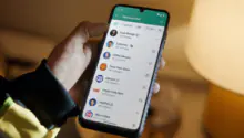 Person holding a smartphone displaying a social app's Discovery Feed with avatars and follower counts.