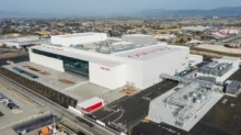 Aerial view of a large white Shiseido manufacturing facility with parking, loading bays, and industrial infrastructure.