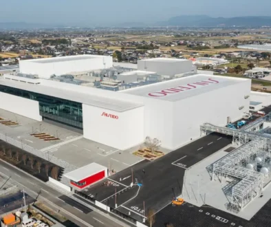 Aerial view of a large white Shiseido manufacturing facility with parking, loading bays, and industrial infrastructure.