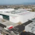 Aerial view of a large white Shiseido manufacturing facility with parking, loading bays, and industrial infrastructure.