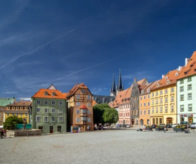 Colorful row of European buildings along a sunny town square with pedestrians on cobblestone pavement