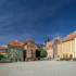 Colorful row of European buildings along a sunny town square with pedestrians on cobblestone pavement