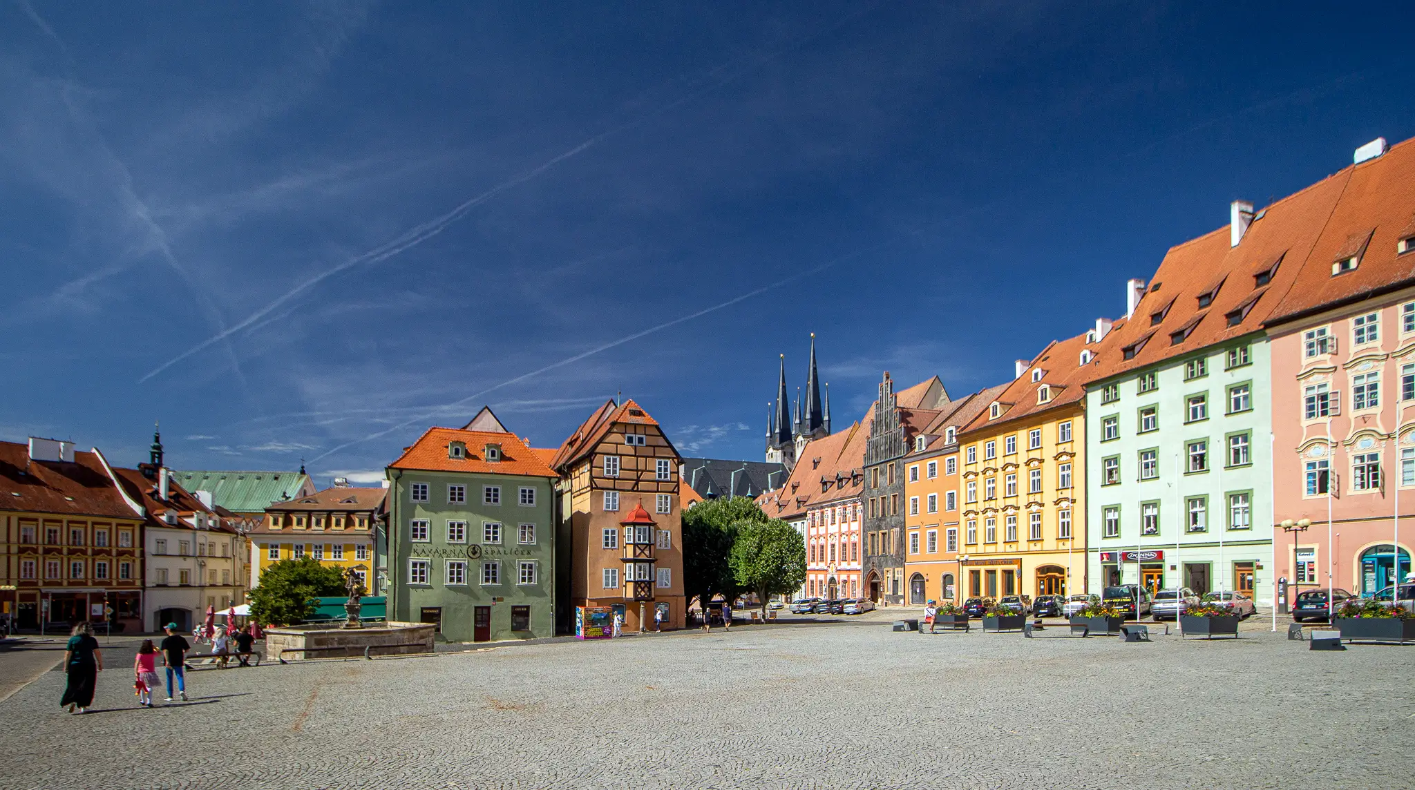 Colorful row of European buildings along a sunny town square with pedestrians on cobblestone pavement