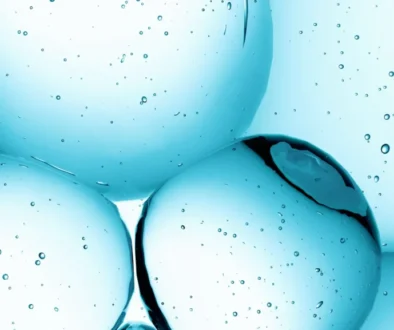 Close-up of blue bubbles suspended in clear blue liquid with smaller bubbles scattered around