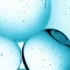 Close-up of blue bubbles suspended in clear blue liquid with smaller bubbles scattered around