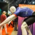 Mannequin in a blue athletic jersey bent forward on a trade show display with people and orange signage in the background.