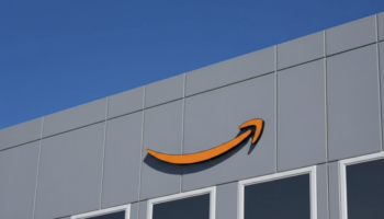 Amazon logo on the gray exterior of a building against a clear blue sky