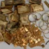 Pile of tarnished gold items: bars, coins, and circular jewelry on a gray background (antique treasure)