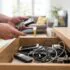 Person standing by an open drawer filled with tangled charging cables and several mobile devices in a living room.