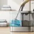 Self-wringing mop bucket with a blue-water reservoir and mop attached, set on a wooden floor beside a front-loading washing machine in a laundry room.