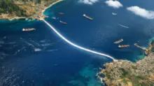Aerial view of a glowing curved white line across the sea, connecting a rocky coastline to a coastal town, with several ships nearby.