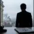 silhouette of a man in a suit facing a rain-soaked city from a window, with a gavel and legal papers on the desk in the foreground