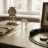 Sepia-toned desk with an antique brass clock, leather notebook, glass prism, framed portrait, a circular toy train on the track, and two pocket watches.