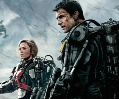 Two soldiers in bulky powered exoskeletons stand on a smoky battlefield, with helicopters in the sky behind them.