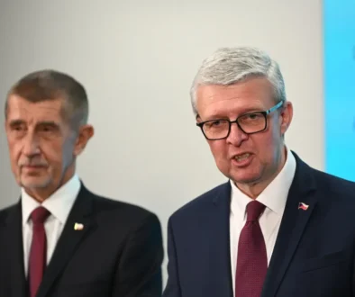 Karel Havlíček stojí vedle Andreje Babiše a mluví.
